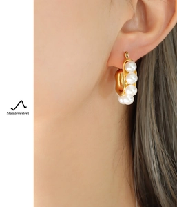 Macro shot of gold-plated stainless steel hoop earrings with four white pearls on ear