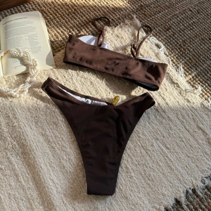 Detailed flat lay of brown ribbed bikini set showing texture on woven texture background