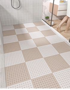 Close-up of beige and white TPE interlocking bathroom floor tiles with drainage holes