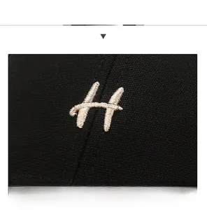 Close-up of premium embroidered H letter on a black canvas baseball cap detail