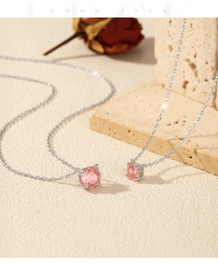 Detailed close-up of pink rose-cut gemstone pendant on silver chain with rose decor
