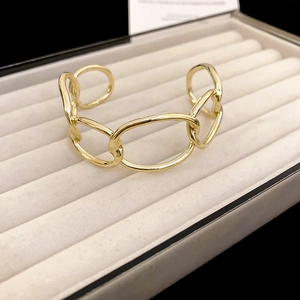 Close-up of polished gold chunky chain cuff bracelet in a gray velvet jewelry box
