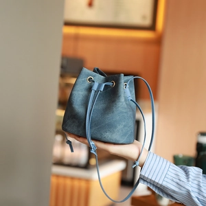 Chic blue denim texture drawstring bucket bag with gold eyelets and slim shoulder strap