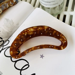 Close-up of tortoiseshell acetate hair claw clip with sparkling rhinestones on a book