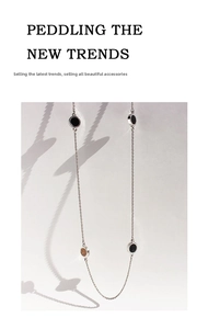 Detail of silver long chain station necklace with black and brown round enamel pendants