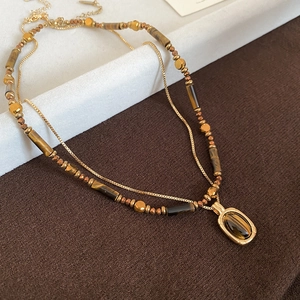 Detail view of double-layered tiger eye stone bead necklace with gold pendant and chain