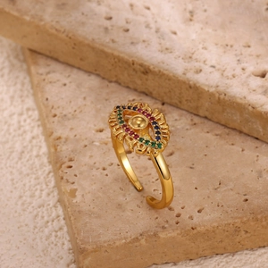 Macro detail of gold plated evil eye ring with colorful zircon stones on stone background