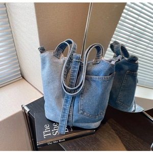 Detailed view of blue denim bucket bag with external pocket and detachable shoulder strap