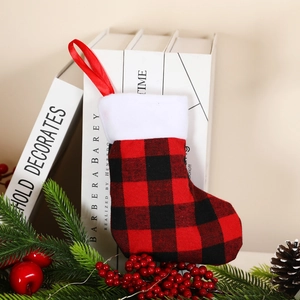 Red and black plaid Christmas stocking with plush trim shown with festive pine decorations