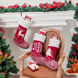 Drei rote gestrickte Weihnachtssocken mit Rentier- und Schneeflockenmustern im Zimmer