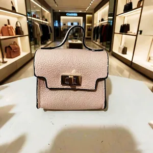 Close-up of pink grained leather mini keychain bag with gold buckle and handle