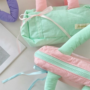 Close-up of quilted macaron color storage bags with cute ribbon bows and zippers