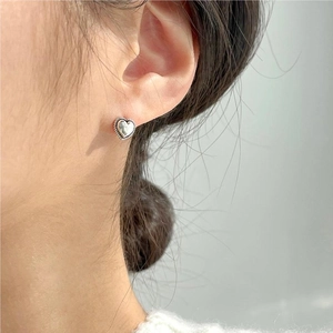 Close-up of heart-shaped twisted silver stud earrings worn on the earlobe
