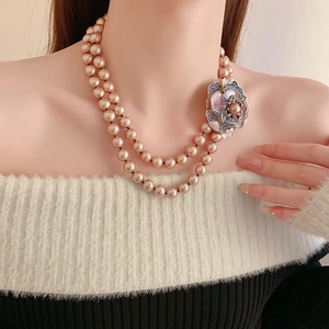 Detail of pink double-layer pearl necklace with purple floral enamel and crystal pendant
