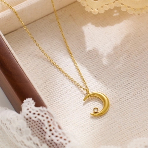 Gros plan du collier pendentif croissant de lune doré avec zircon sur fond de tissu rustique