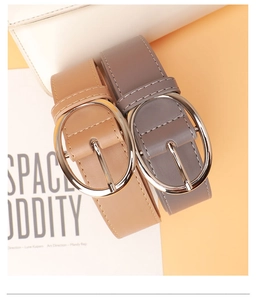 Detail of grey and camel PU leather belts with silver oval buckles on a magazine