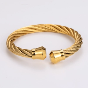 Detailed close-up of a gold-plated twisted cable cuff bracelet with geometric end caps