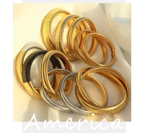 Close-up of industrial style textured metal coil bangles in gold and silver finish