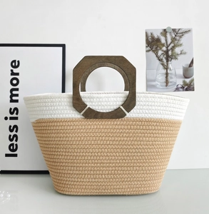 Detail of a two-tone woven cotton tote bag featuring a round natural wooden handle