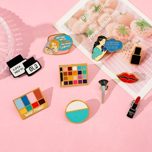 Macro shot of colorful makeup-themed enamel pins including eye shadow and lipstick shapes