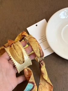 Detailed close-up of matte gold vintage hollow cuff featuring a sunflower silk fabric wrap