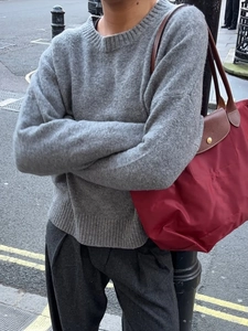 Street style view of a light gray round neck long sleeve knit sweater for women