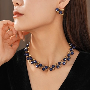 Close-up of vintage gold necklace and earring set with blue stones and pearls on a model