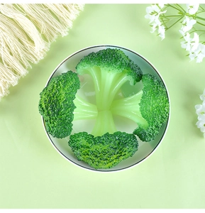 Top-down view of realistic artificial broccoli model on a white plate with floral decor