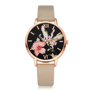Detail of rose gold watch with floral dial pattern and beige leather strap