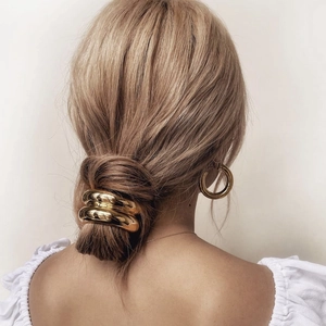 Close-up of a large wavy golden metal hair clip securing a stylish low bun on a model