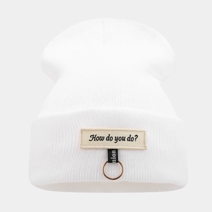 Detail of white knit beanie featuring iron ring and 'How do you do' embroidery