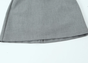Detailed macro view of the hem stitching and satin texture on a grey bow dress