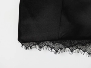 Détail de la dentelle délicate et du satin lisse sur l'ourlet de la robe noire