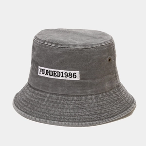 Close-up of washed gray denim bucket hat featuring white FOUNDED1986 embroidery patch