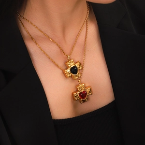 Close-up of gold cross necklaces with black and red heart stones on a twisted chain