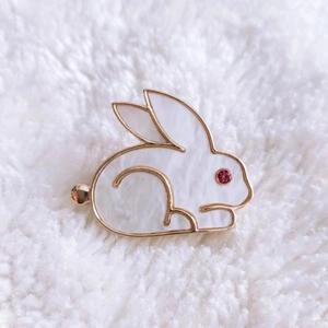 Close-up of golden bunny brooch with white pearl inlay and red crystal eye detail