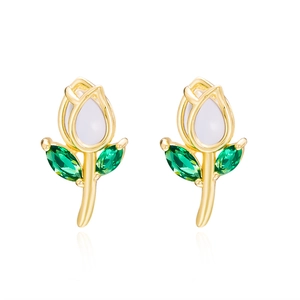 Close-up of golden tulip earrings with white petal inlay and sparkling green crystals