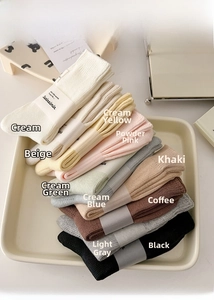 Detailed stack of ribbed cotton socks in cream and pastel tones with paper band