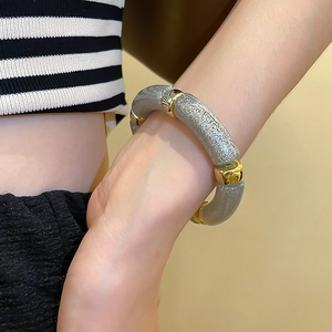 Detailed shot of an acrylic iridescent bracelet with gold metal links on a model's wrist