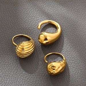 Detailed view of three polished gold rings with drop, ribbed, and textured irregular patterns