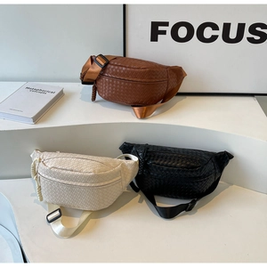 Detailed view of three woven texture chest bags in brown, cream, and black on a white stand