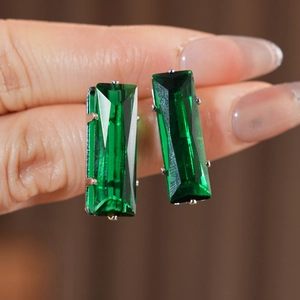 Close-up of emerald green rectangular zircon studs with silver prong setting for women