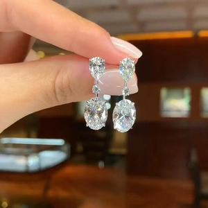 Macro shot of silver teardrop earrings featuring a large oval stone and brilliant cut gems