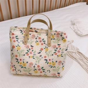 Detail view of floral canvas tote bag with quilted texture and brown leather handles