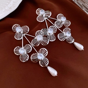 Close-up of floral drop earrings with silver petals, cubic zirconia and teardrop pearls