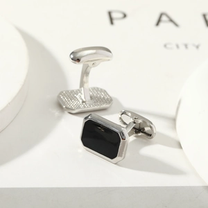 Detailed close-up of silver and black rectangular cufflinks on a minimalist background
