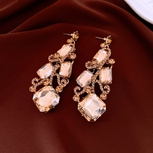 Detail of luxury champagne crystal drop earrings with intricate gold-plated filigree patterns
