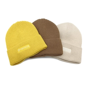 Detailed texture of knit beanies in ginger, coffee, and beige with brand embroidery
