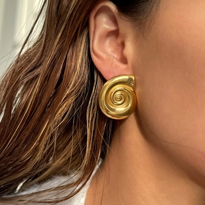 Close-up of golden spiral shell earrings with vintage satin finish on model
