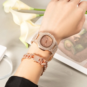 Rose gold watch and Cuban chain bracelet set with crystals on a lifestyle background